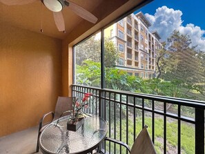 A balcony with a glass table, chairs, and a potted plant. - 3BR Orlando Resort | Heated Pools | 3 mi Disney (Orlando)