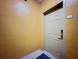 A door with a number plate, a textured wall, and a floor mat. - 3BR Orlando Resort | Heated Pools | 3 mi Disney (Orlando)