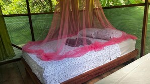 Una cama con dosel, un edredón estampado y almohadas.