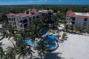A resort with multiple buildings, a central swimming pool, and surrounding palm trees. - Salty Breeze Suite|Seaview Family Residence w/Pool (San Pedro)