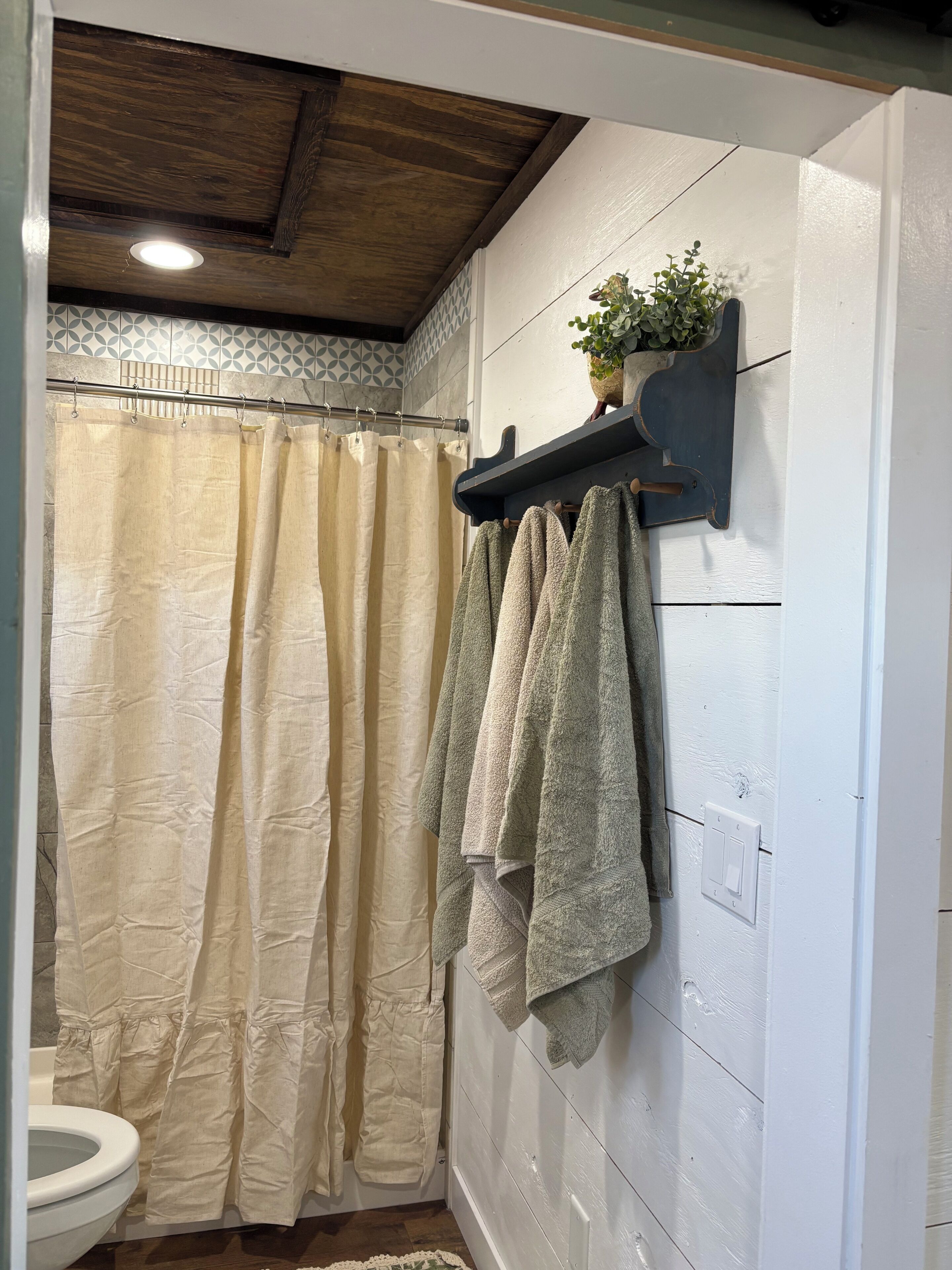 A bathroom with a shower curtain, a toilet, and towels hanging on a rack.