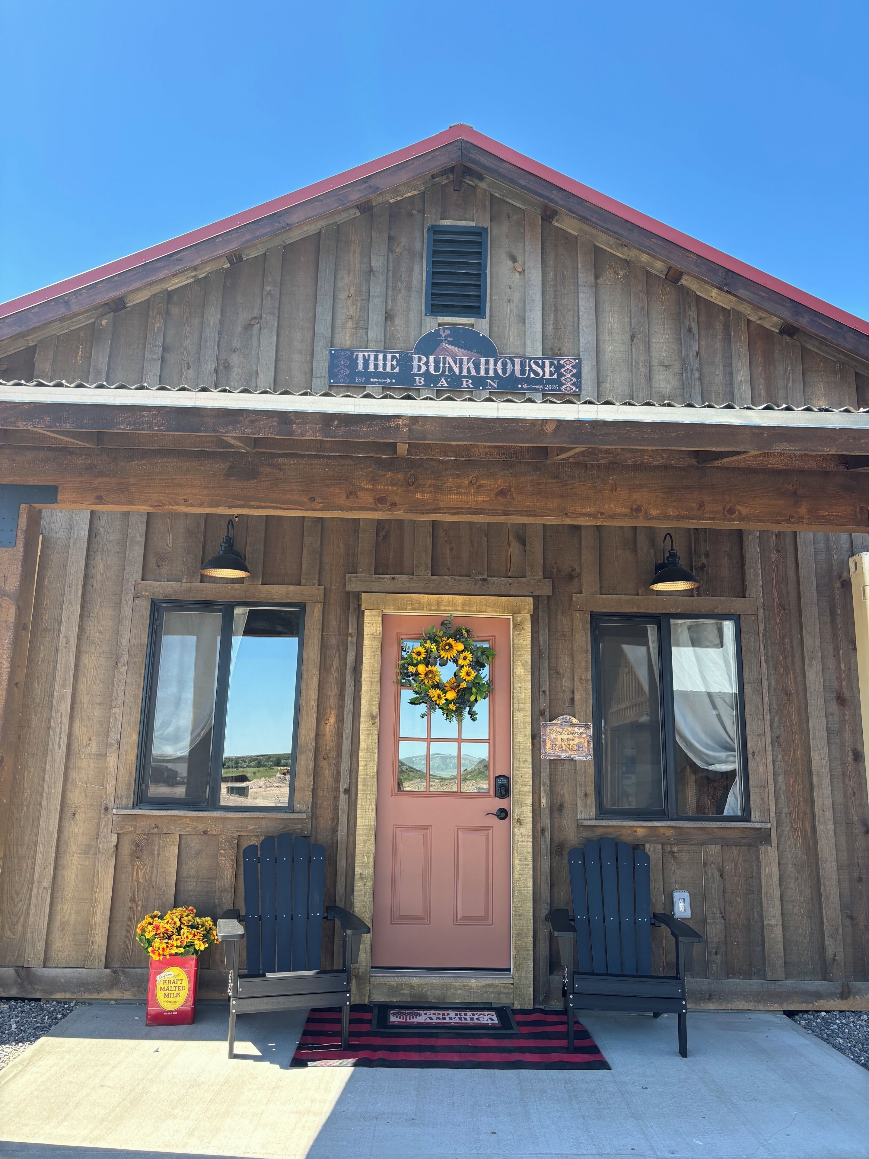 A wooden building with a red roof and a sign that reads 'The Bunkhouse Barn.'