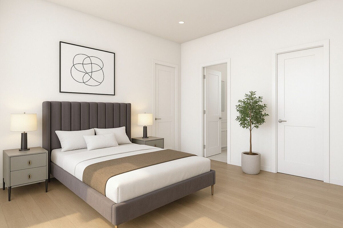 A modern bedroom with a large bed, bedside lamps, a potted plant, and a framed artwork on the wall.
