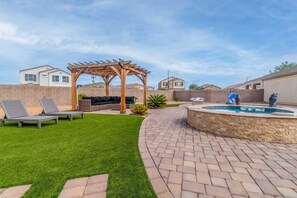 Ein Garten mit einer Holzpergola, einem Pool und einem gepflegten Rasen.