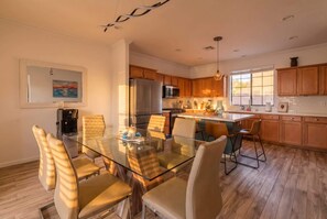 A modern kitchen with wooden cabinets, stainless steel appliances, and a glass dining table with chairs. - Phoenix Luxe! Stylish Home! Pool & Hot Tub! Gated community (Phoenix)