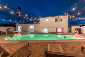 A swimming pool with inflatable toys, string lights, and a pink flamingo float. - The Desert Palm! Private Oasis! Heated Pool (Glendale)