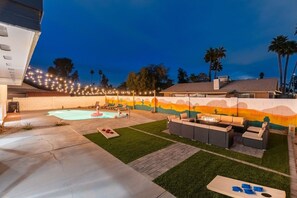 Ein Garten mit Swimmingpool, Gartenmöbeln und Wandgemälde.