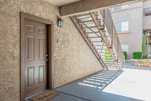 A residential building with a brown door, a welcome mat, and a metal staircase leading to an upper level. - Fountain Hills Retreat!Pool! Hot Tub! Mountain Views! (Fountain Hills)
