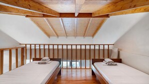 A room with two beds, wooden beams on the ceiling, and a window. - Villa 'Kalirroe' in Marathiás (Marathiás)