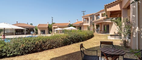 A residential area with a swimming pool, outdoor seating, and a clear sky.