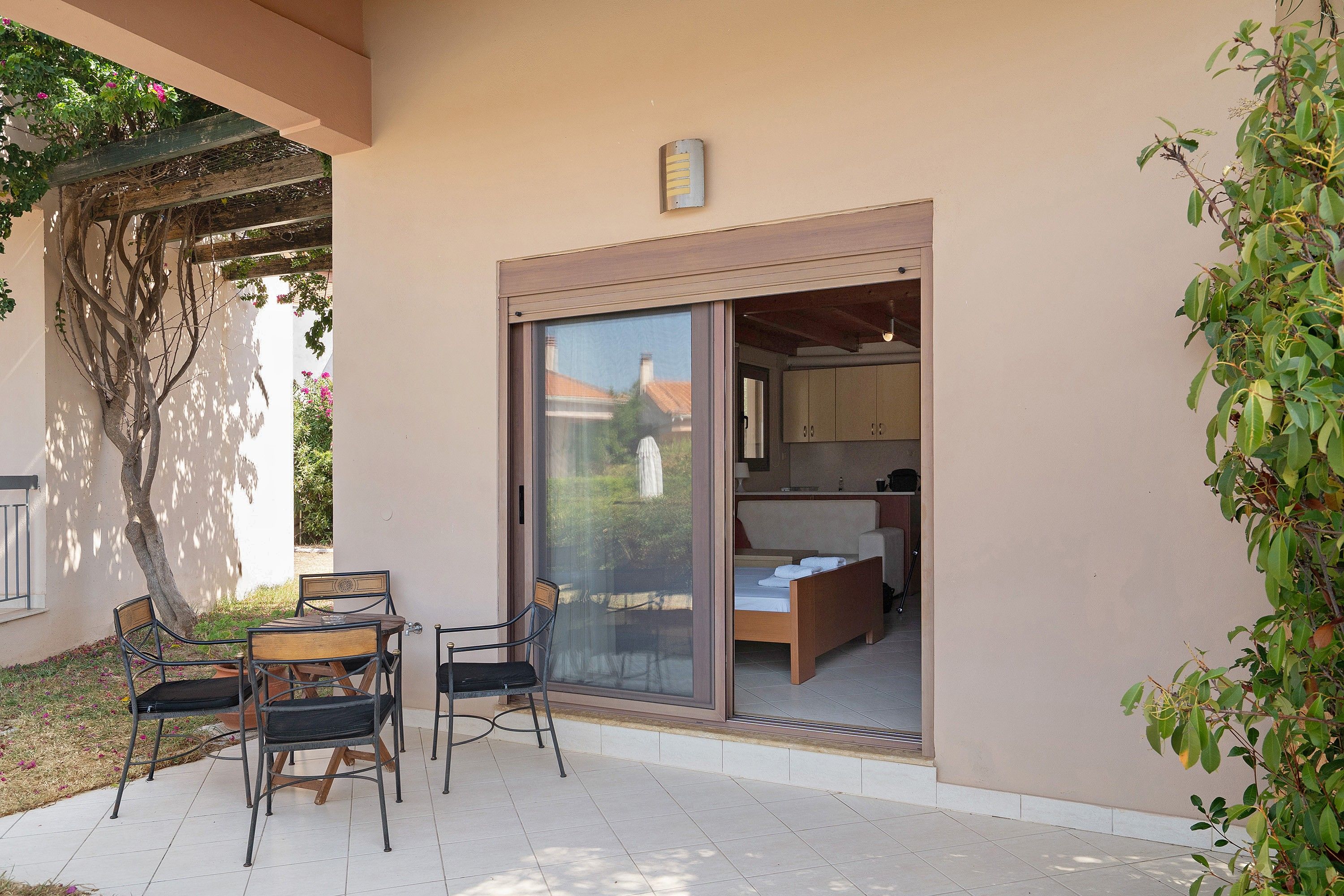 Ein Zimmer mit einer Schiebetür und einem Balkon, ein Bett, ein kleiner Tisch und zwei Stühle.