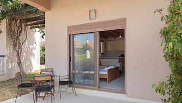 Ein Zimmer mit einer Schiebetür und einem Balkon, ein Bett, ein kleiner Tisch und zwei Stühle.
