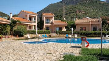 Un espace piscine avec des chaises longues et une vue dégagée sur une montagne en arrière-plan.