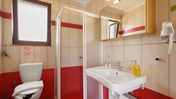 Ein Badezimmer mit Toilette, Waschbecken, Spiegel und Dusche.