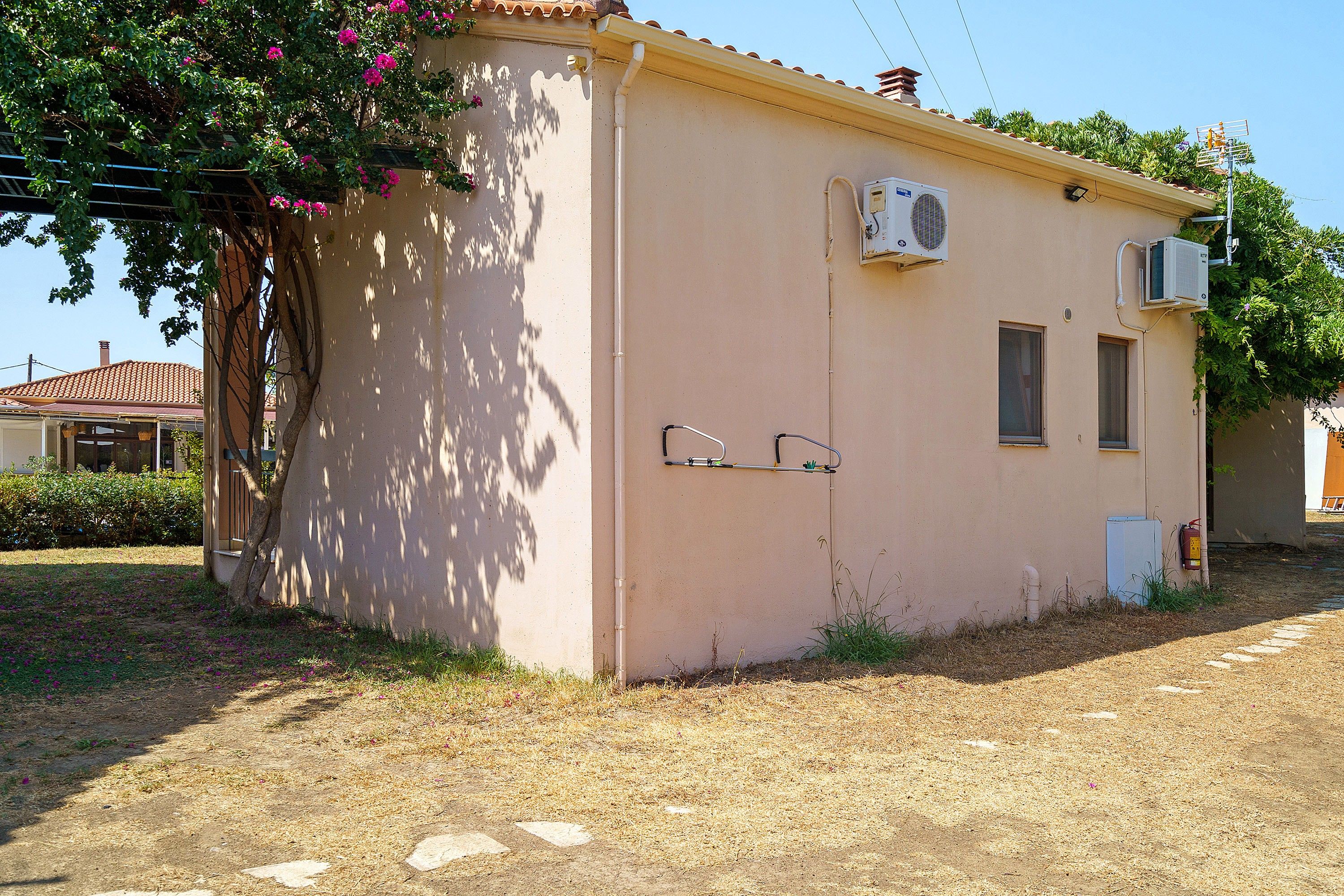 A small building with a single window, an air conditioning unit, and a fire extinguisher.