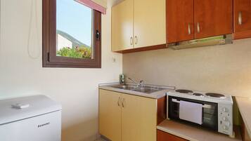 A compact kitchen with a built-in oven, a microwave, and a small refrigerator.