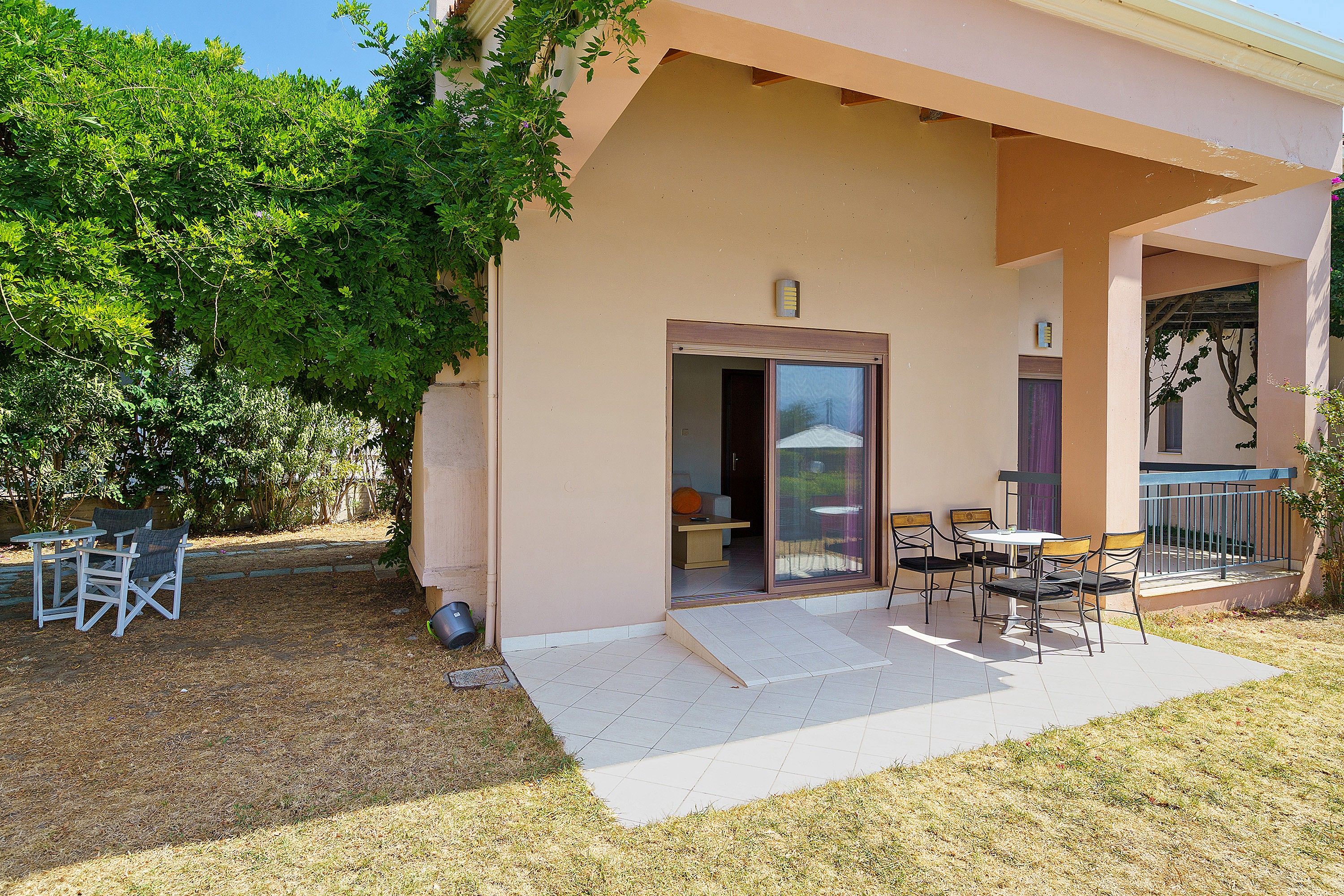 A building with a covered patio area, outdoor seating, and a door leading to an interior space.
