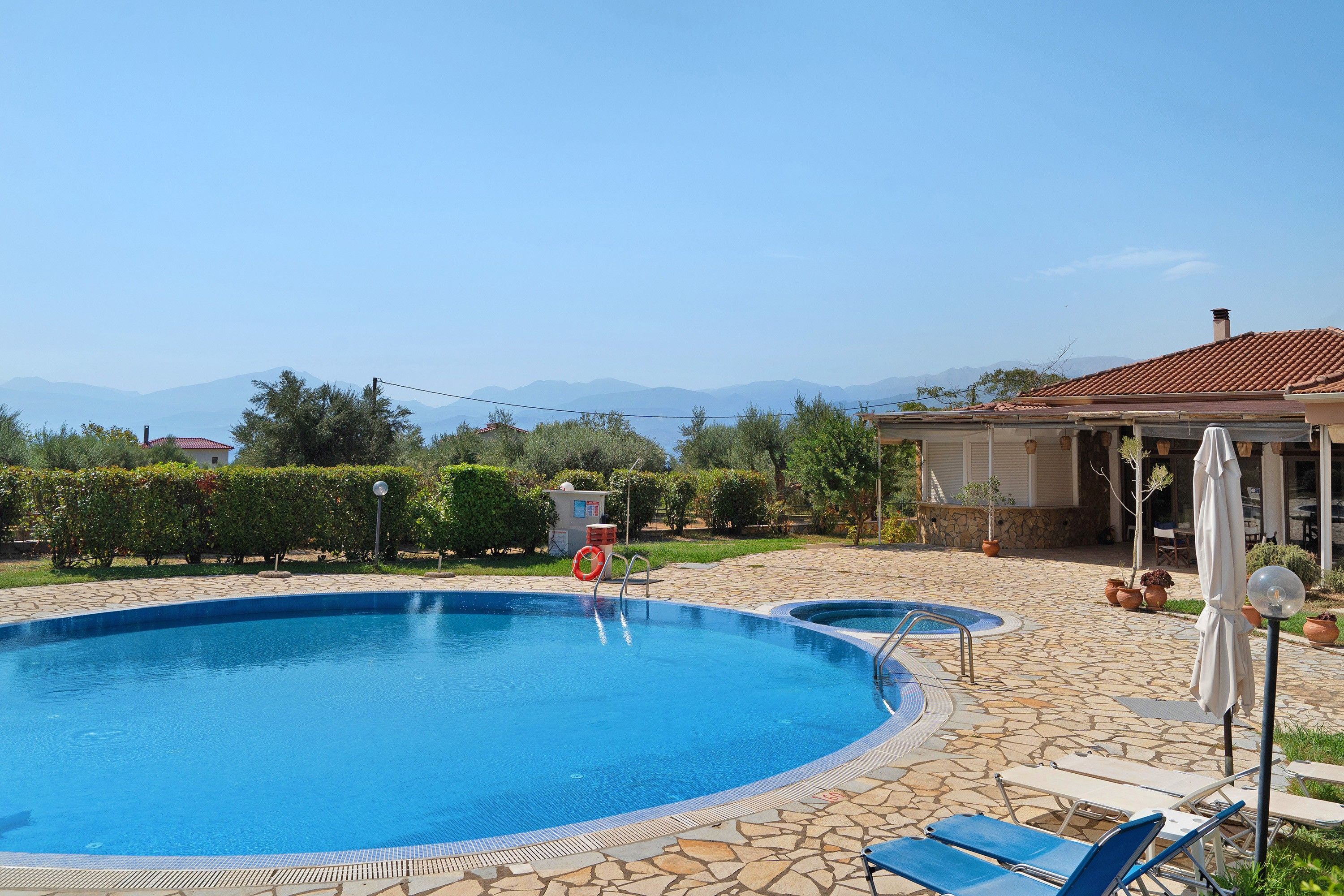 En swimmingpool med en kant av sten, en livboj och solstolar.