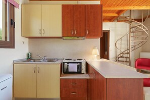 Una cocina compacta con armarios de madera, un microondas integrado y una pequeña encimera.
