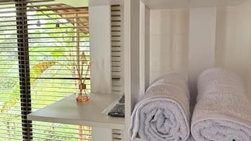 Une chambre avec un lit, une table et une étagère où sont pliés des serviettes.
