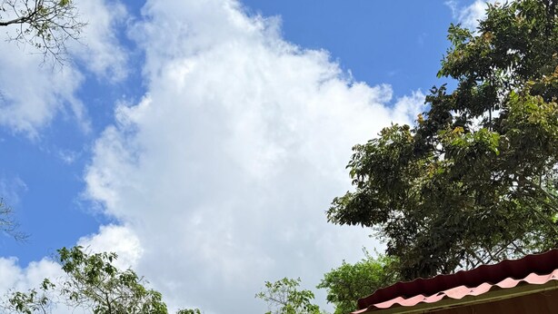 A two-story house with a red-tiled roof, a balcony, and a wooden porch. - Cozy La Chorrera Cabin Surrounded by Nature with a View of the Mountains (Venecia)