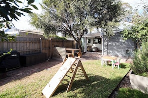 A backyard with a wooden deck, a wooden ladder, a barbecue grill, and a covered seating area. - The Merri Classic Victorian Home by Walking Trails (Northcote)