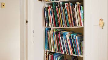 A bookshelf filled with books in a room with wooden flooring and white walls.