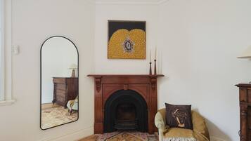 A room with a fireplace, a mirror, a chair, and a rug.