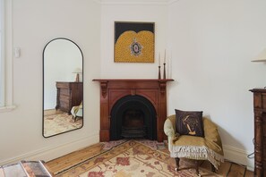 Ein Zimmer mit Kamin, Spiegel, Stuhl und Teppich.