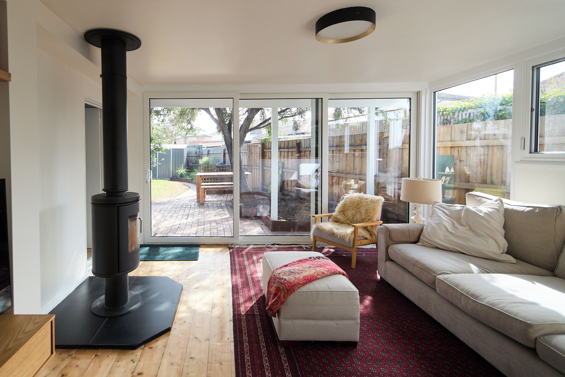 A modern living room with a sofa, a chair, a fireplace, and a view through glass doors to an outdoor patio.