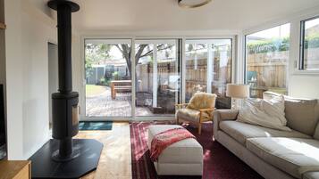 A modern living room with a sofa, a chair, a fireplace, and a view through glass doors to an outdoor patio.