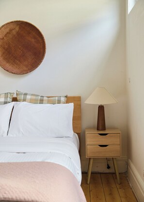 A bedroom with a bed, a nightstand with a lamp, and a wall-mounted round mirror. - The Merri Creekside Living near Cafs and Culture (Northcote)