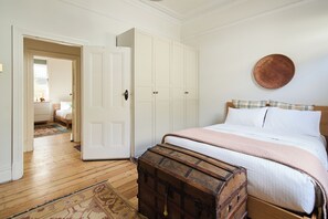 A bedroom with a wooden bed, a chest of drawers, a wardrobe, and a round wall decoration. - The Merri Classic Victorian Home by Walking Trails (Northcote)