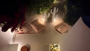 A well-lit outdoor seating area with a cactus sculpture, a small fountain, and a wall-mounted planter with greenery.