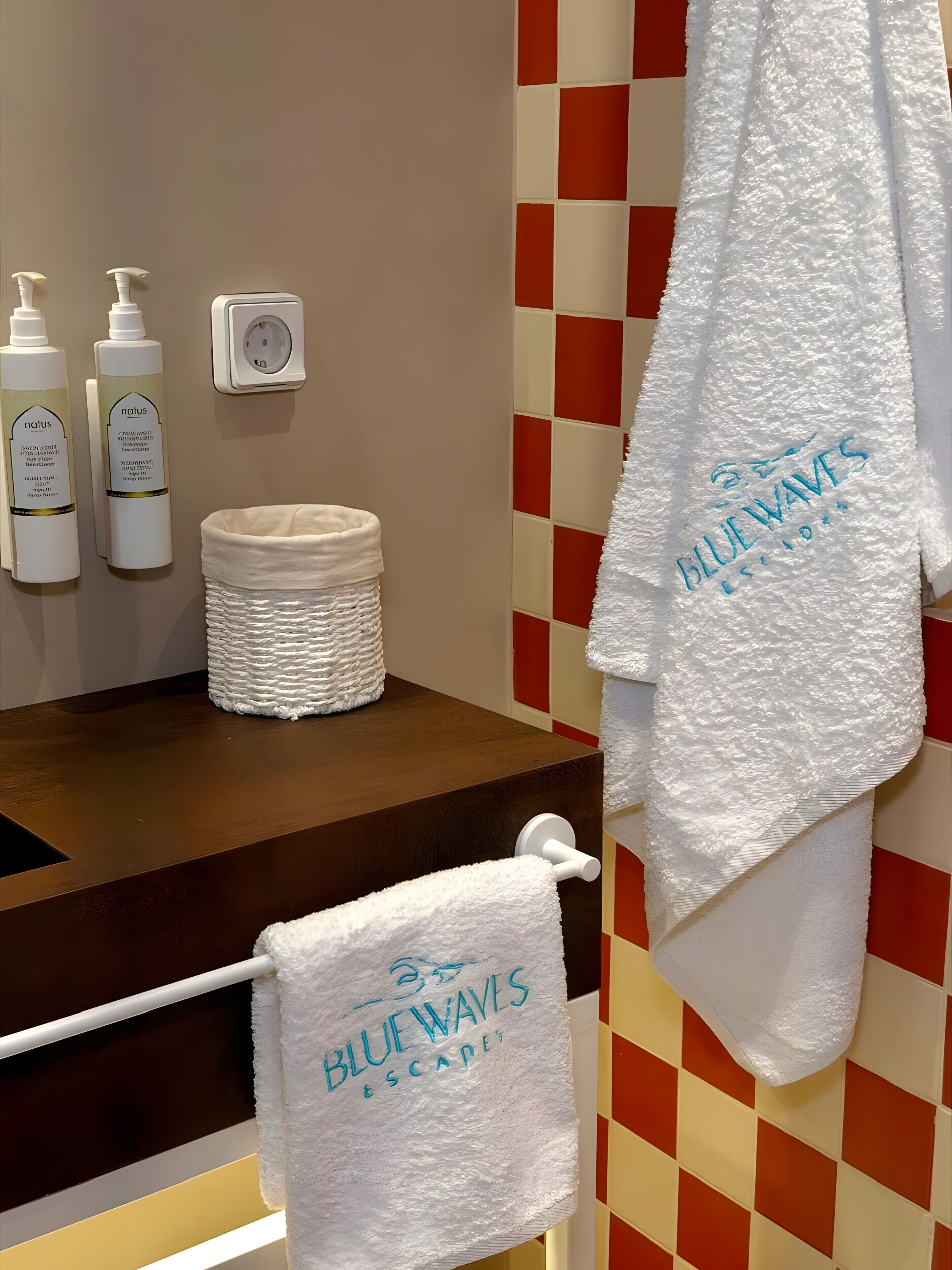 A bathroom with a towel rack, a white towel, and two bottles of lotion.