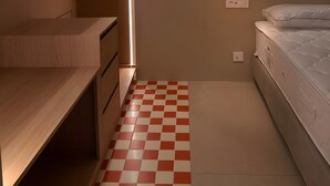Une chambre à coucher avec un lit, une table de chevet, un luminaire suspendu et un sol à carreaux.