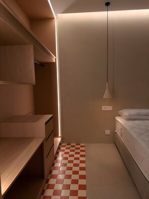 A bedroom with a bed, a bedside table, a hanging light fixture, and a checkered floor.