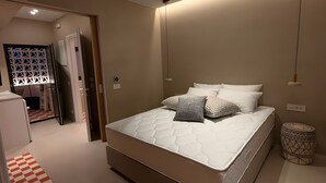 A bedroom with a bed, a ceiling fan, a bedside table, and a patterned rug. - Holiday Home 'Antiparos Moonstone Jacuzzi' with Wi-Fi and Air Conditioning (Antiparos)