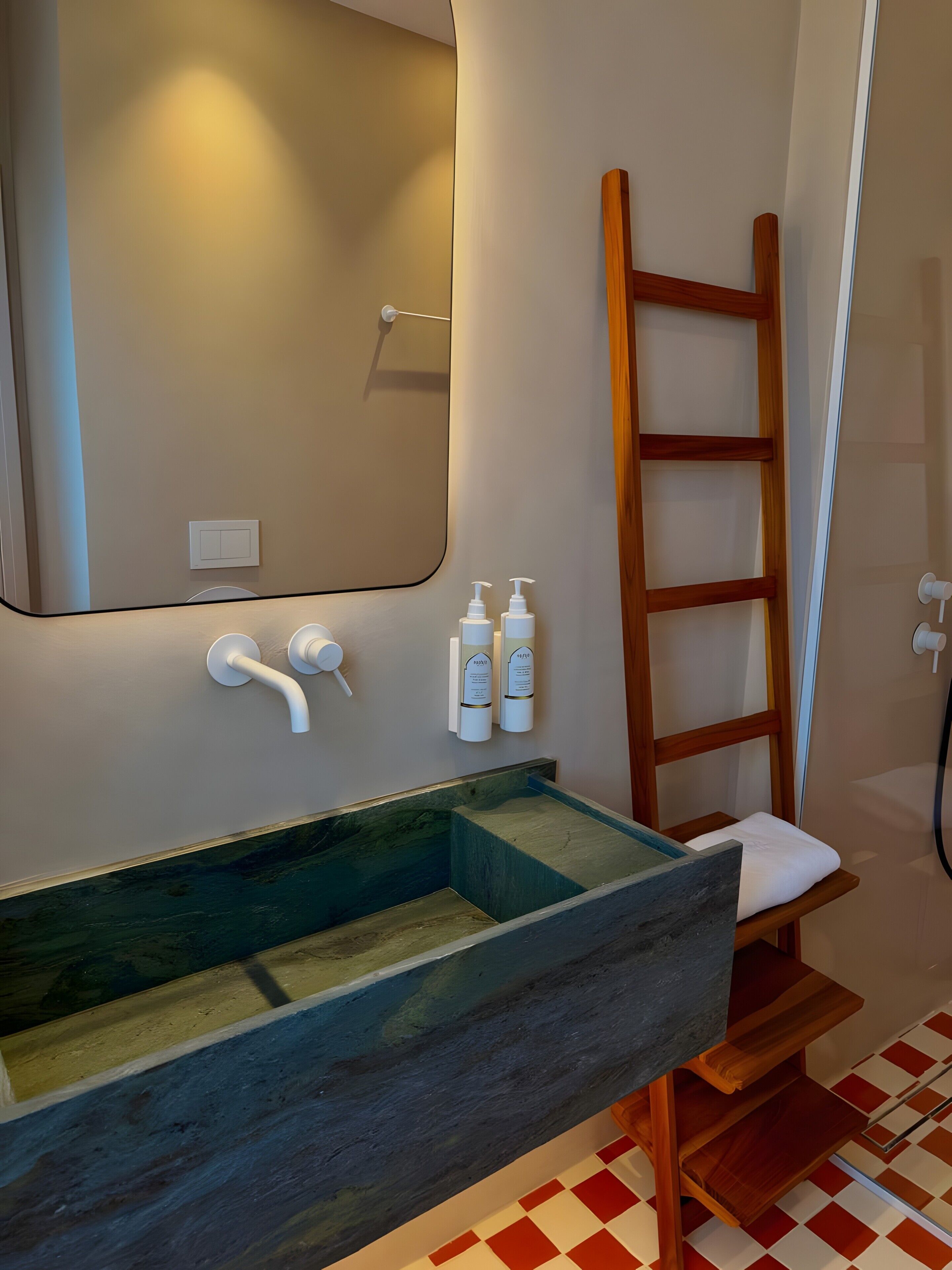 Une salle de bain avec un meuble-lavabo en bois, un grand miroir et une échelle en bois.