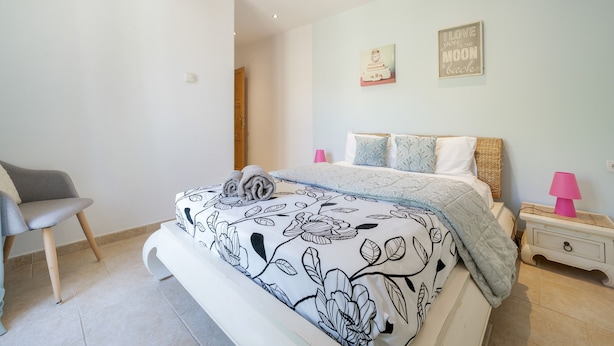 Una camera da letto con un letto, una sedia, un comodino e due elementi decorativi a parete.