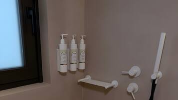 Une salle de bain avec une douche, une fenêtre et trois bouteilles de shampoing accrochées au mur.