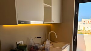 A modern kitchen with white cabinetry, a built-in oven, and a sink. - Holiday Home 'Bluewaves Sunstone Terrace House' with Private Garden, Balcony and Wi-Fi (Antiparos)