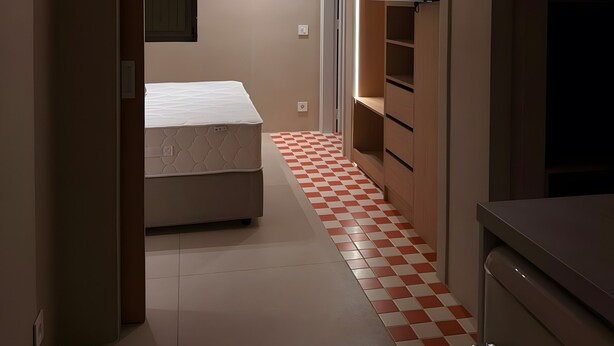 A narrow hallway with a checkered floor, a bed, a ceiling fan, recessed lighting, and a television mounted on the wall. - Holiday Home 'Bluewaves Sunstone Terrace House' with Private Garden, Balcony and Wi-Fi (Antiparos)