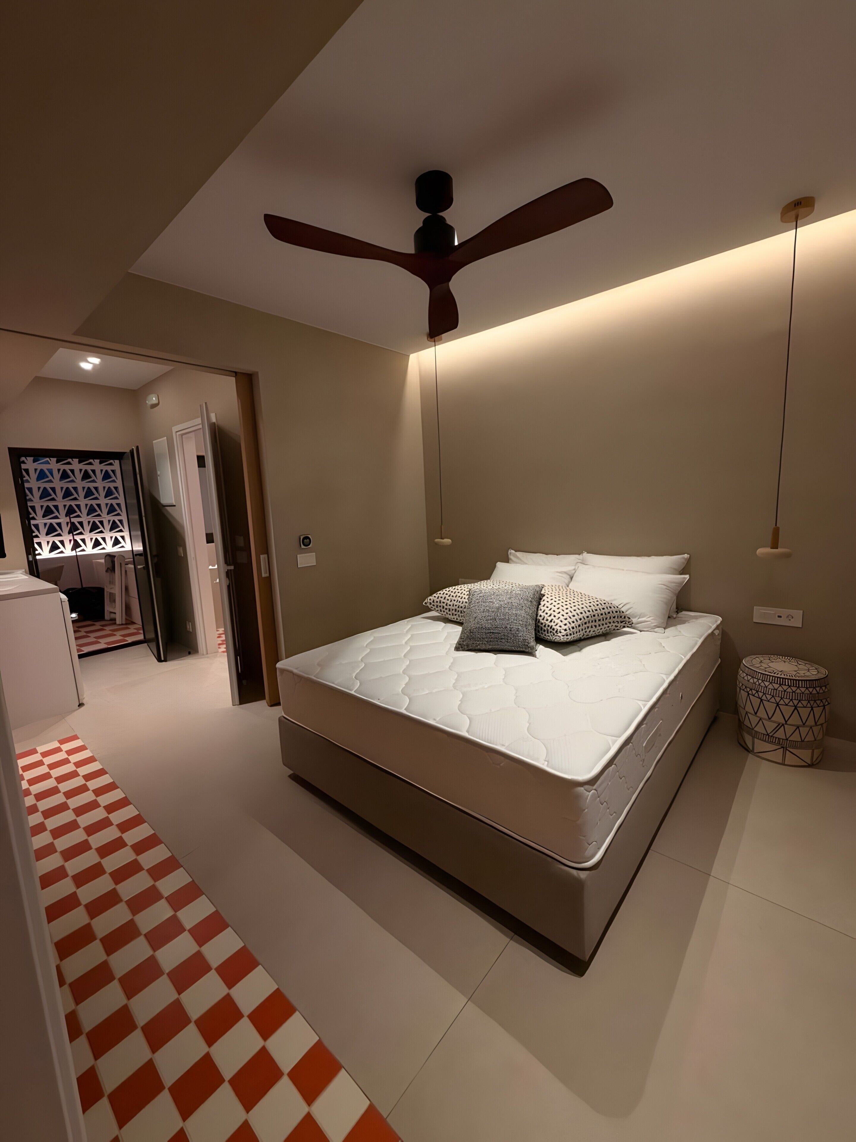 Une chambre à coucher avec un lit, un ventilateur de plafond, une table de chevet et un tapis à motifs.