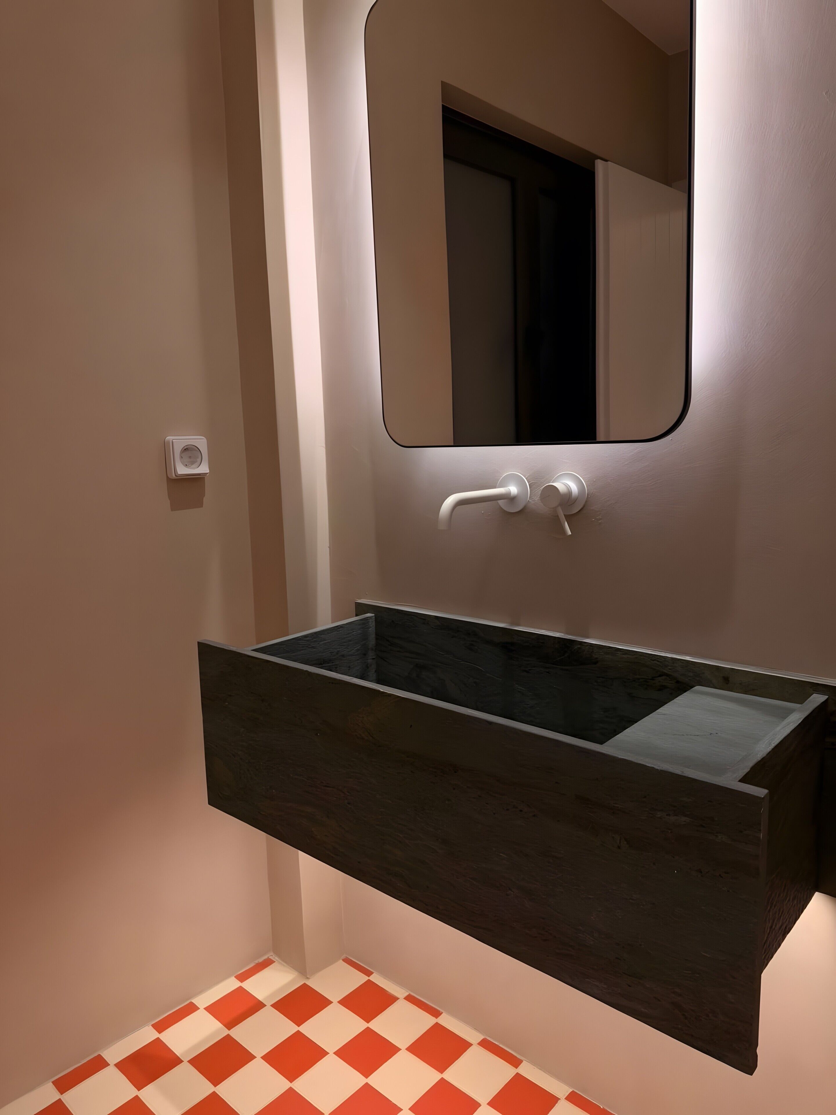 A bathroom with a dark wood vanity, a white wall-mounted mirror, and a checkered floor.