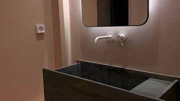 A bathroom with a dark wood vanity, a white wall-mounted mirror, and a checkered floor.