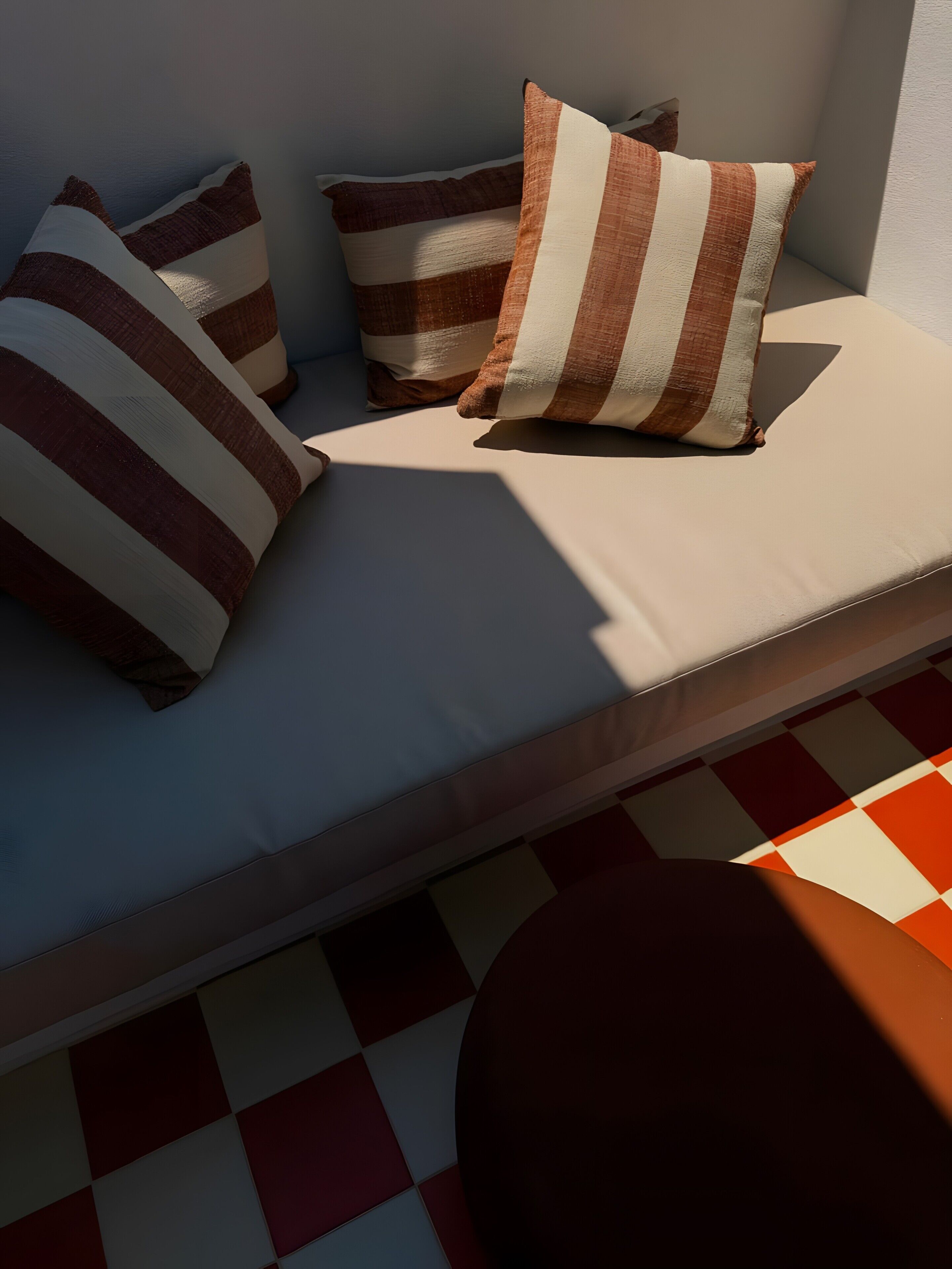 A sofa with striped cushions and a checkered floor.