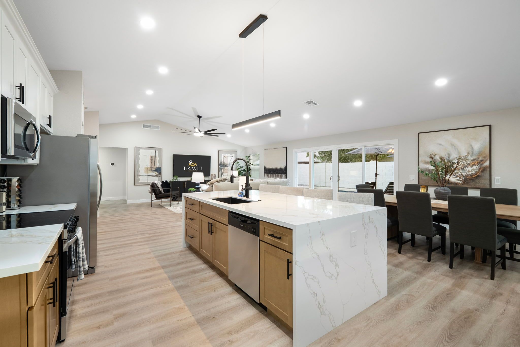 Una cocina moderna con una isla de mármol, armarios de madera y un comedor con mesa y sillas.
