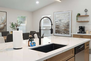 A modern kitchen with a black sink, white countertops, and a coffee machine. - NEW|Desert Springs @Westgate|Designer Pool Retreat (Glendale)