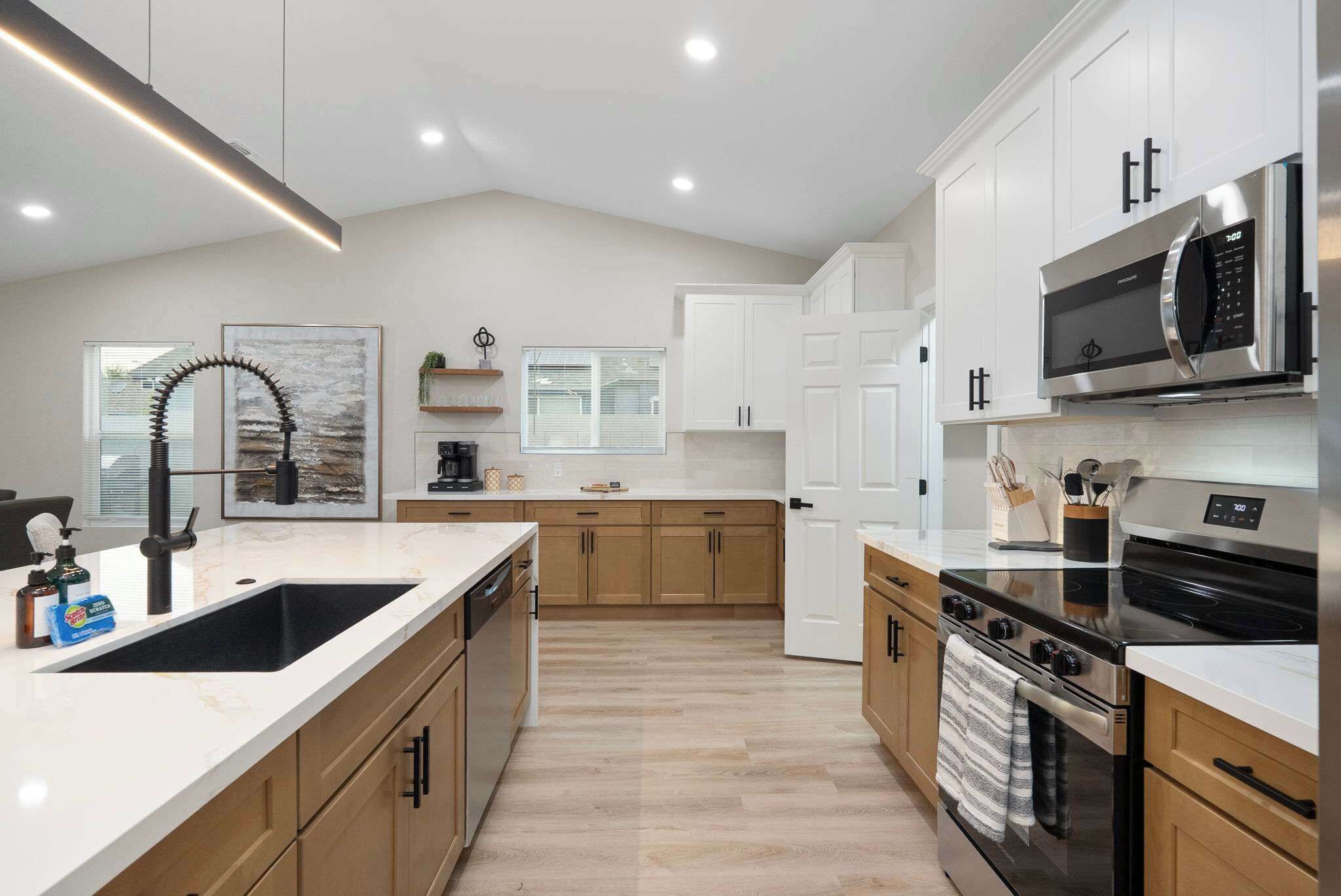 Une cuisine moderne avec des meubles blancs, une cuisinière en acier inoxydable et un grand îlot central doté d’un évier.